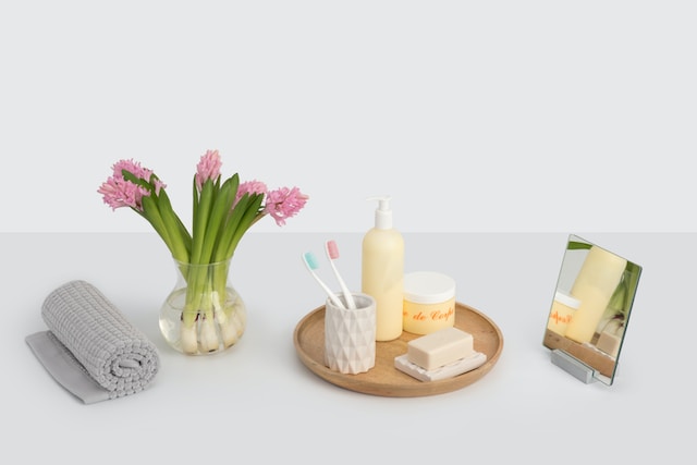 Hotel toiletries on a wooden tray beside tulips